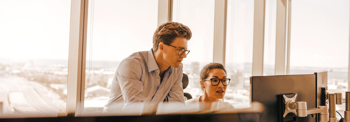 Two office workers looking at computer