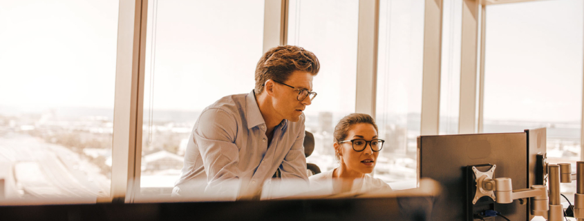 Two office workers looking at computer