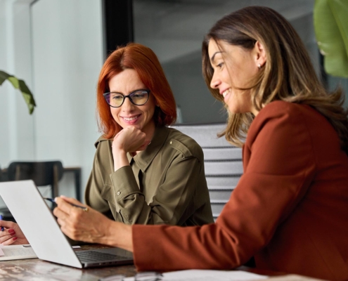 Two professionals in office collaborating on laptop